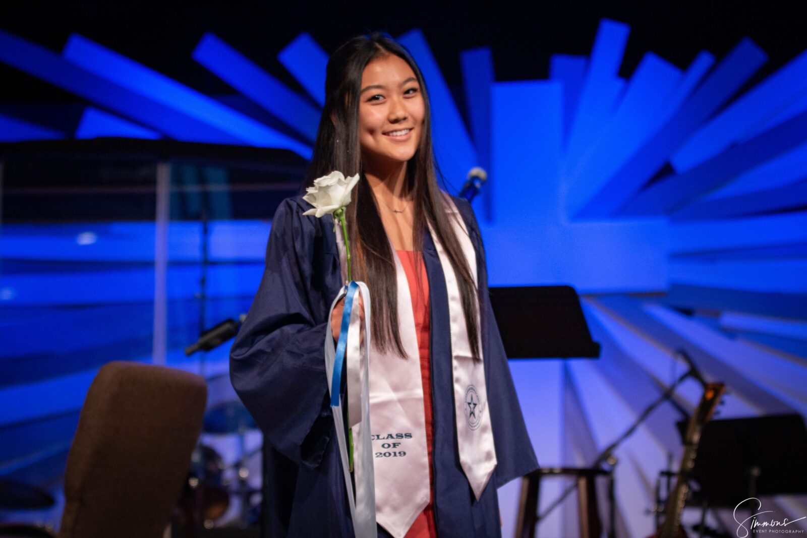 A woman in graduation gown holding a ribbon.