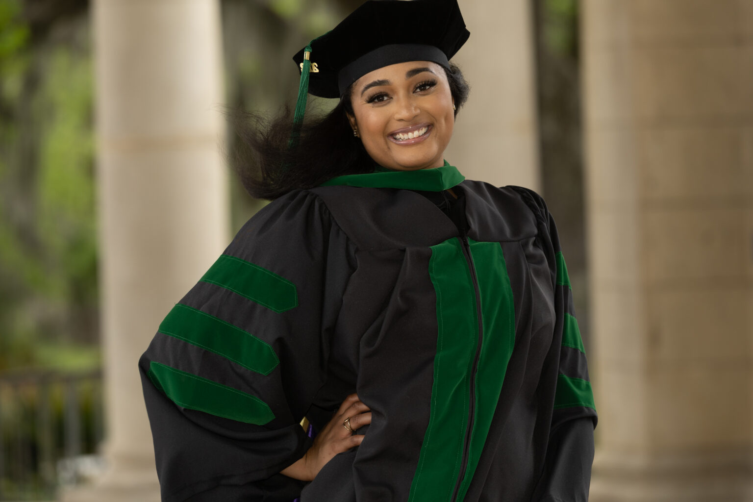 A woman in graduation gown and cap posing for the camera.