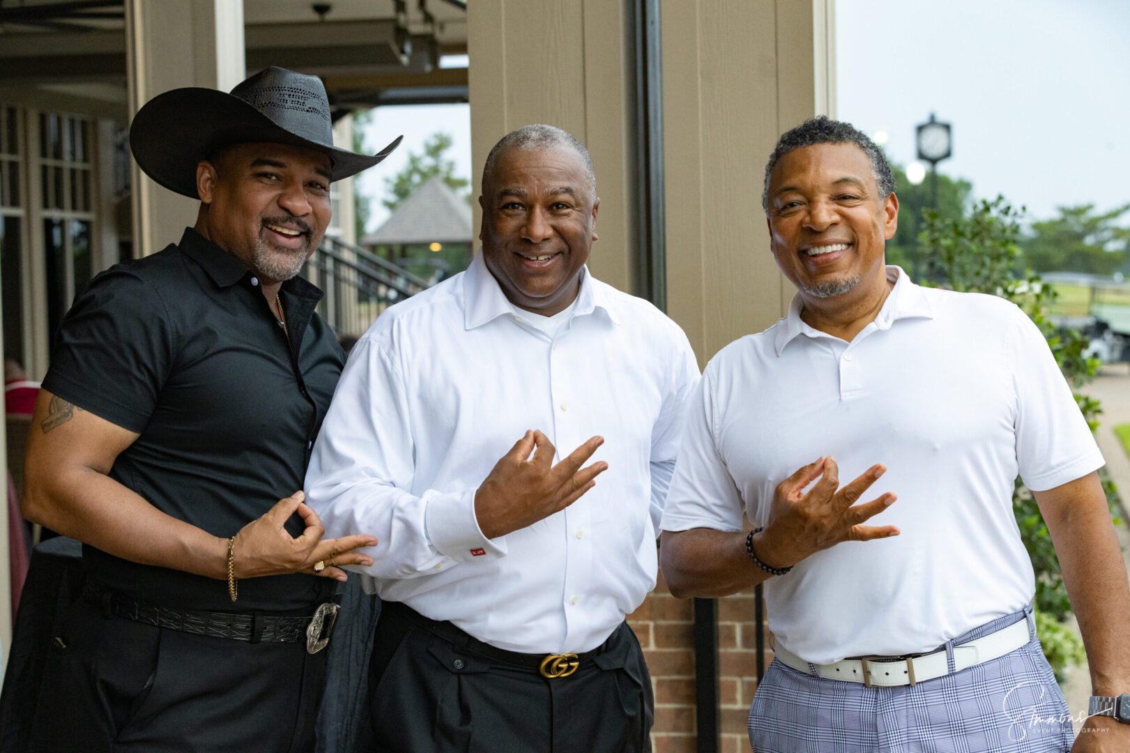 Three men standing next to each other in front of a building.