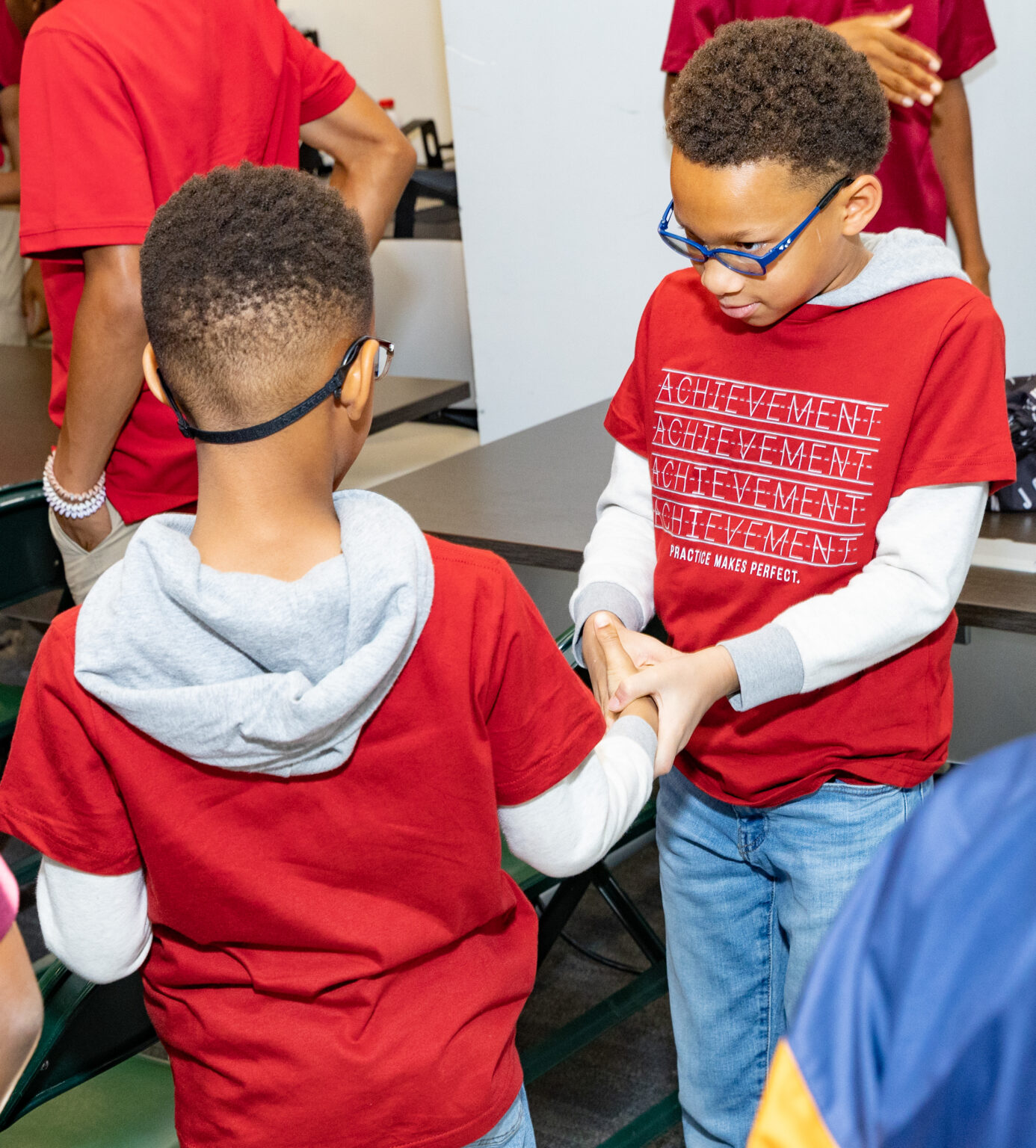 Two young boys are holding hands and playing a game.